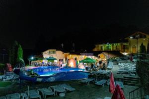 a swimming pool at night with people sitting around it at Спа Комплекс Ливадите in Deredzhik-Kʼoy