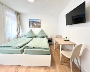a white bedroom with a bed and a table at Apartment Brunnenstraße in Braubach in Braubach