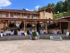 a restaurant with white and yellow tables and chairs at Спа Комплекс Ливадите in Deredzhik-Kʼoy