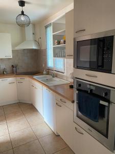 a kitchen with a microwave oven and a sink at Maison mitoyenne proches des plages in Bénesse-Maremne