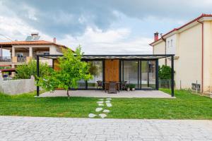 a house with a black roof and a green yard at Morera Suite Paliouri in Paliouri