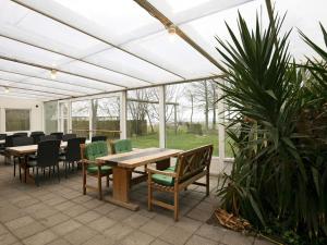 a patio with a wooden table and green chairs at 14 person holiday home in Løgstør-By Traum in Løgstør +27 photos