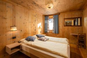 a bedroom with a bed in a wooden wall at Engadina Chalet in Livigno