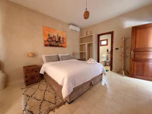 a bedroom with a bed and a painting on the wall at Villa Tiziri in Essaouira +43 photos