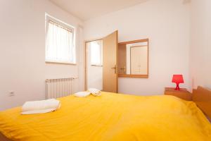 - un grand lit jaune dans une chambre blanche avec un miroir dans l'établissement Apartment Darko, à Rovinj
