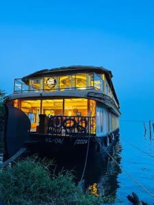 a boat sitting on the water with lights on at Aarush road lines and holidays in Alleppey