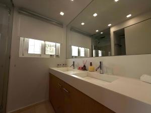 Dream View Vouliagmeni في أثينا: حمام به مغسلتين ومرآة كبيرة