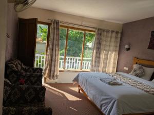 a bedroom with a bed and a chair and a window at White Apricot Lodge in Baltit