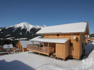 a wooden cabin with a snow covered roof in the snow at Chalet in Hohentauern am Skilift in Hohentauern