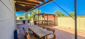 a patio with a wooden table and benches at Sunrises Kalbarri in Kalbarri