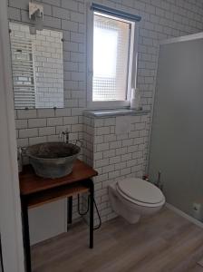 Un baño con lavabo, inodoro y ventana. en L'Atelier, 