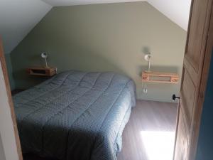 a bedroom with a bed with a blue comforter at L'Atelier in Coupray