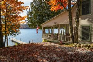 a house on the shore of a lake with a flag at Charming 1-bedroom Waterfront Cottage in Morgan VT in Morgan