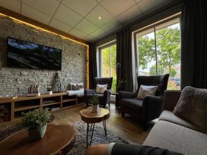 a living room with a couch and chairs and a tv at Hotel am Bergl in Schweinfurt