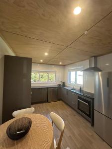 Il comprend une cuisine équipée d'une table et d'un réfrigérateur. dans l'établissement Lake Maraetai Escape, à Mangakino