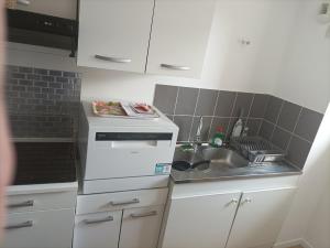 Una pequeña cocina con fregadero y estufa. en grand appartement dans résidence sécurisée, en Beuzeville 4 fotos más