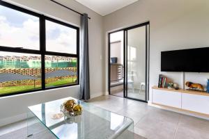 a living room with a tv and a glass table at AlimamaSpaces The Chelsea's Munyaka in Midrand