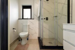 a bathroom with a toilet and a glass shower at AlimamaSpaces The Chelsea's Munyaka in Midrand +22 photos