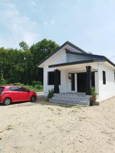 une voiture rouge garée devant une maison dans l'établissement Aqilla Homestay Besut, à Kampung Kuala Besut