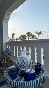 ein Tisch mit einer Teekanne und Schüsseln mit Essen in der Unterkunft A Luxurious & Cozy Apartment Greek Village Marassi in El-Alamein