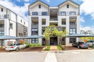 ミッドラントにあるAlimamaSpaces The Munyakas Manson 1543の駐車場に傘を置いたアパートメントビル