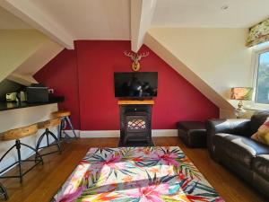 a living room with a red wall with a fireplace at The Eaves in Lynton, Exmoor, Devon in Lynton