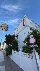 a white building with a sign on a fence at Hostal Playa Hidalgo in Rota +20 photos