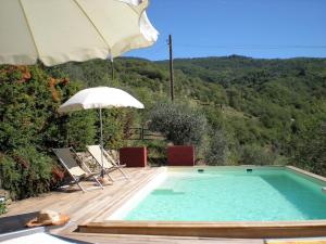 ein Pool mit einem Sonnenschirm, 2 Stühlen und einem Sonnenschirm in der Unterkunft Farmhouse in Cortona in Cortona