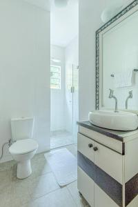 ein weißes Badezimmer mit Toilette und Waschbecken in der Unterkunft Camburi 5 quartos com piscina natural in Camburi + 133 Fotos