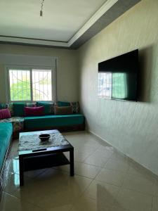 a living room with a green couch and a table at Appart situé au centre de Martil ,moderne près de la plage ,de l'aéroport Tetouan et vue sur lac in Martil