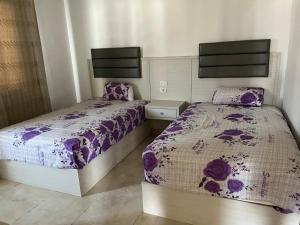 - 2 lits dans une chambre avec couette violette dans l'établissement Modern Stylish 2BR Apartment Fully Equipped 3Beds at Celia TMG New Administrative New Capital, à Madīnat al Amal