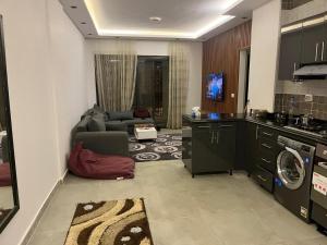 Il comprend une cuisine et un salon avec un canapé et un lave-linge. dans l'établissement Modern Stylish 2BR Apartment Fully Equipped 3Beds at Celia TMG New Administrative New Capital, à Madīnat al Amal