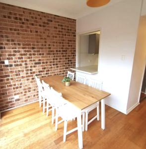 een houten tafel met witte stoelen en een bakstenen muur bij FlexiRoom on Hereford in Sydney +9 foto's