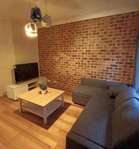 een woonkamer met een bank en een bakstenen muur bij FlexiRoom on Hereford in Sydney