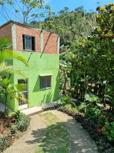 a green house with a pathway leading to it at Teresópolis Hostel in Teresópolis