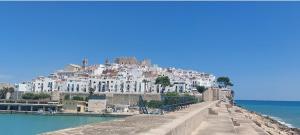 a town on top of a hill next to the water at CALA HOUSE I Espacioso apartamento céntrico, aire acondicionado y parking incluido in Peñíscola