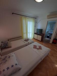 a bedroom with two beds and a television at Apartmants Emy in Novalja