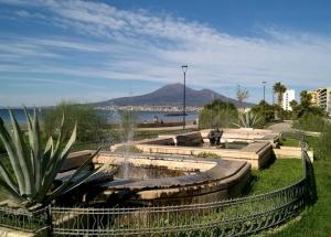 a park with a water fountain in front of a beach at Oleander Apartment in Castellammare di Stabia