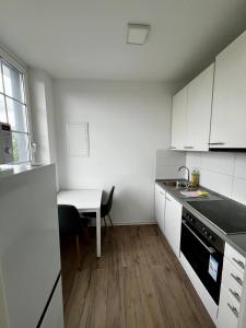 a kitchen with white cabinets and a table and a sink at Ferienwohnung 302 am Kasinopark in Georgsmarienhütte +6 photos