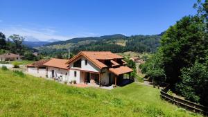 a house on a hill with a green field at Reguero Gato Turismo Rural in Candamo