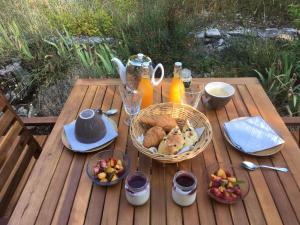 a picnic table with a basket of bread and juice at Maisonnette en forêt à 5min du centre ville in Forcalquier