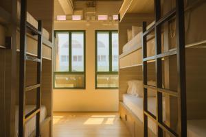 a room with bunk beds and two windows at Wink at Upper Cross Street in Singapore