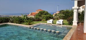 a swimming pool with two chairs and a house at villa star hill Tanger in Tangier