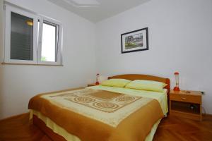 a bed in a white room with a window at Apartments Vila Ana in Seline