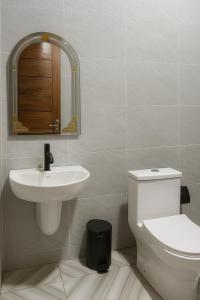 a bathroom with a sink and a toilet and a mirror at Brand New Royals Retreat 2BR 3BA in Oyarifa
