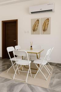 a white dining room with a table and chairs at Brand New Royals Retreat 2BR 3BA in Oyarifa +16 photos