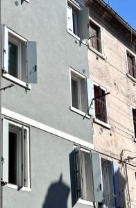 a building with open windows and a shadow on the side at Suite Apartment a tema Natale in centro storico "Gingerbread Suite" in Chioggia +32 photos