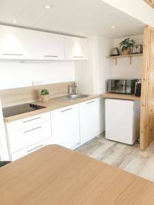 a kitchen with white cabinets and a white refrigerator at Le Pouget , Studio, Rez de Chaussée, Front de Mer WIFI in Le Touquet-Paris-Plage