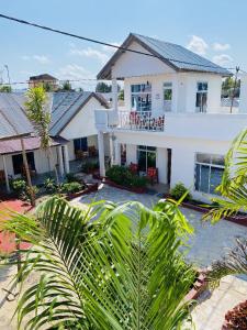 a white house with palm trees in front of it at Karibu House Paje in Paje