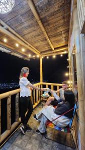 a woman standing on a balcony with a group of people at RIYA Tesoro de la montaña Cabaña Armonia in Ibagué